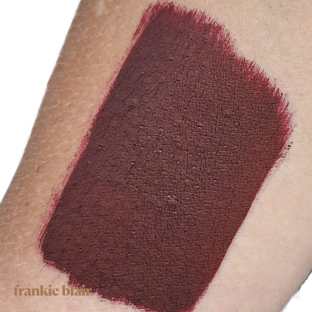 Frankie Blair Lennox Matte Lip Stain swatch on arm, a dark chocolate brown with berry undertone lip stain.